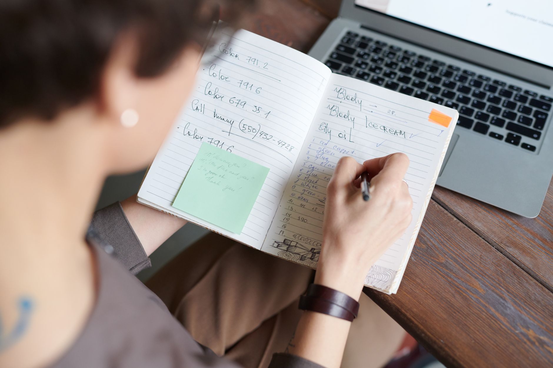 A freelancer writing a list of repetitive business tasks on paper at a desk