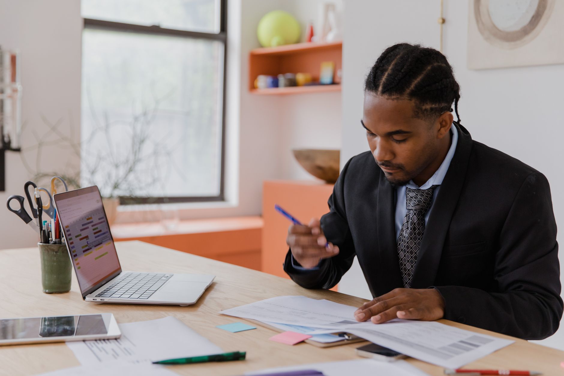 A business owner sitting at a desk and reviewing digital invoices on a laptop with a calculator nearby
