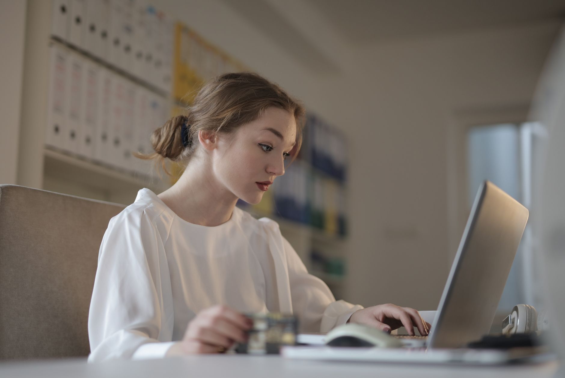 A freelancer reviewing invoices and bank statements on a laptop at a tidy desk