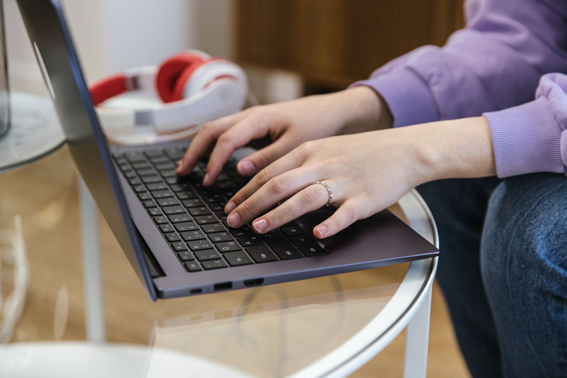 A person typing an email draft on a laptop in a sunlit home office